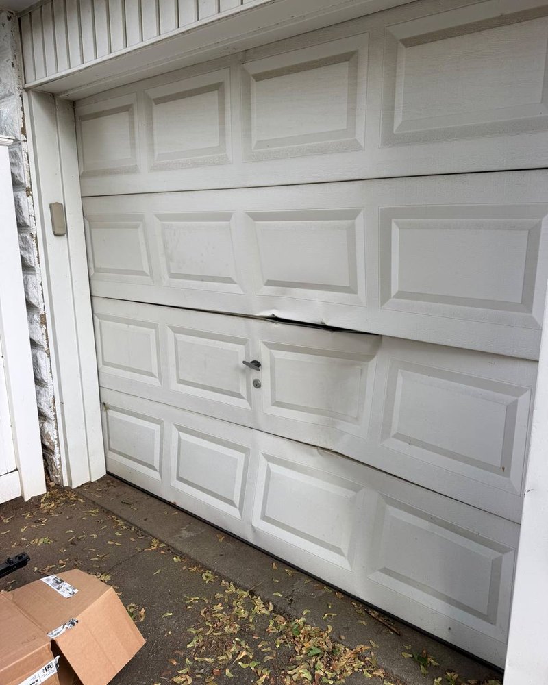 Damaged residential garage door before replacement by NorthLine Garage Doors