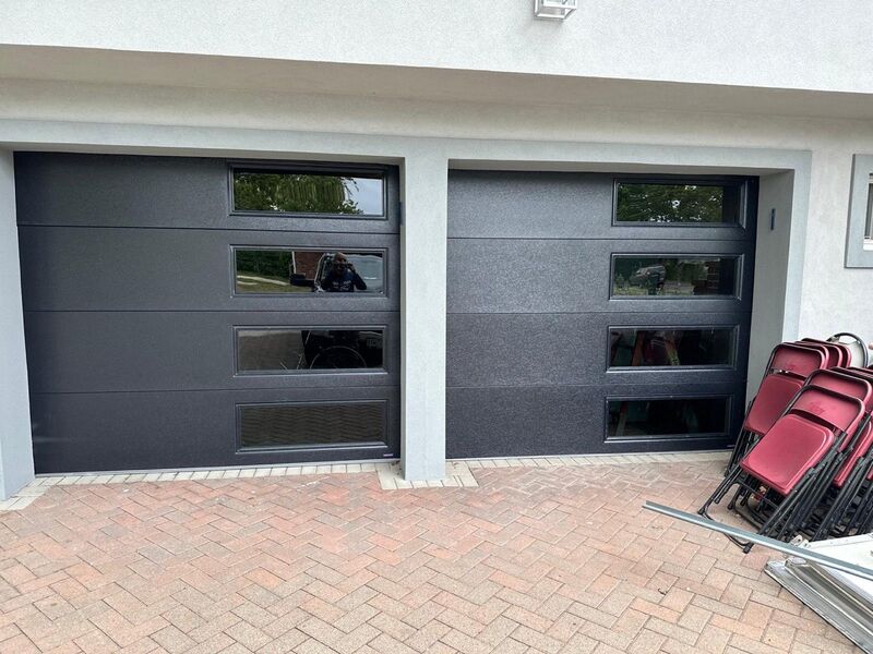 Two charcoal garage doors side by side, each with a column of windows